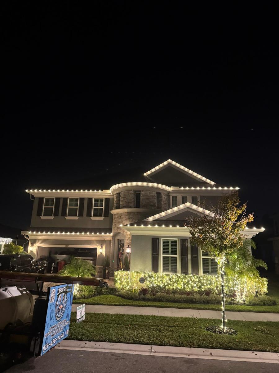 Two-story home with roofline lights and a wrapped tree